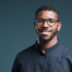 Portrait of handsome African-American man wearing glasses and looking at camera smiling while posing against deep blue background, copy space